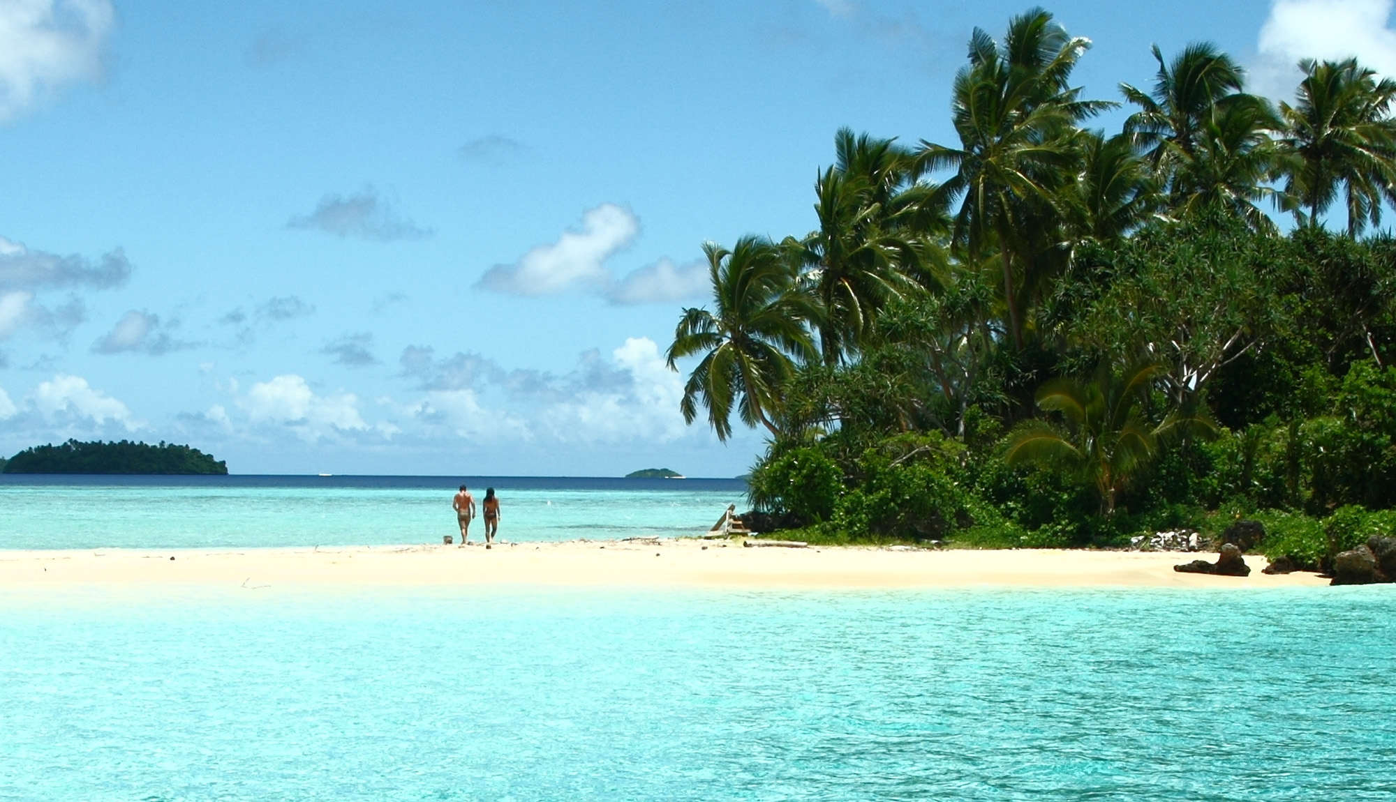 Couple walking on a white sandy beach in Tonga