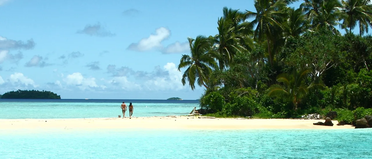 Couple walking on a white sandy beach in Tonga