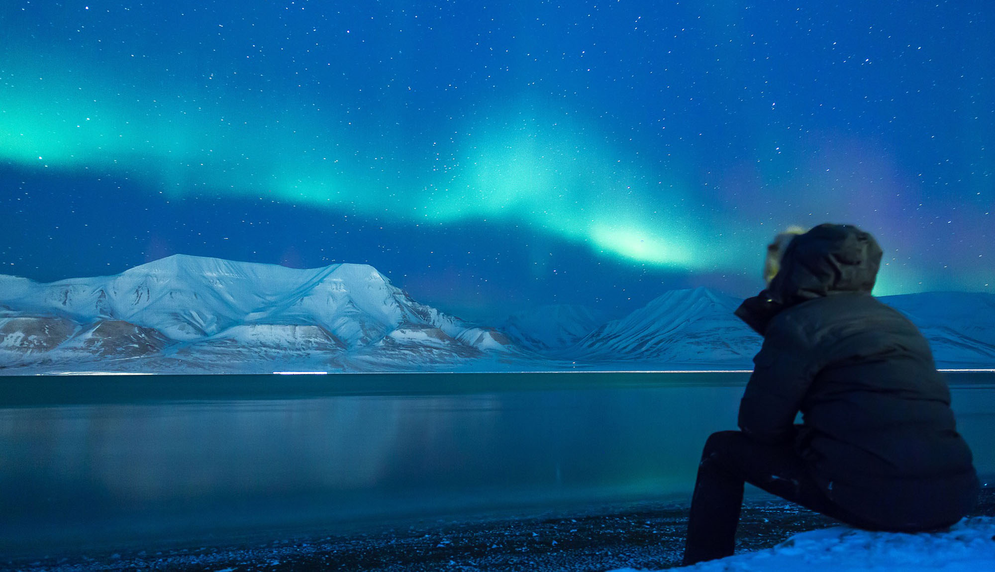 Person watching the Aurora Borealis dancing above the mountains