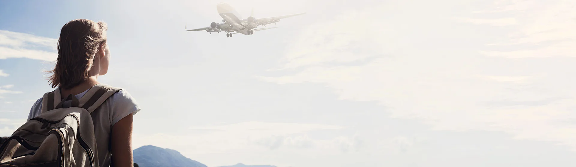 Woman near sea watching a plane